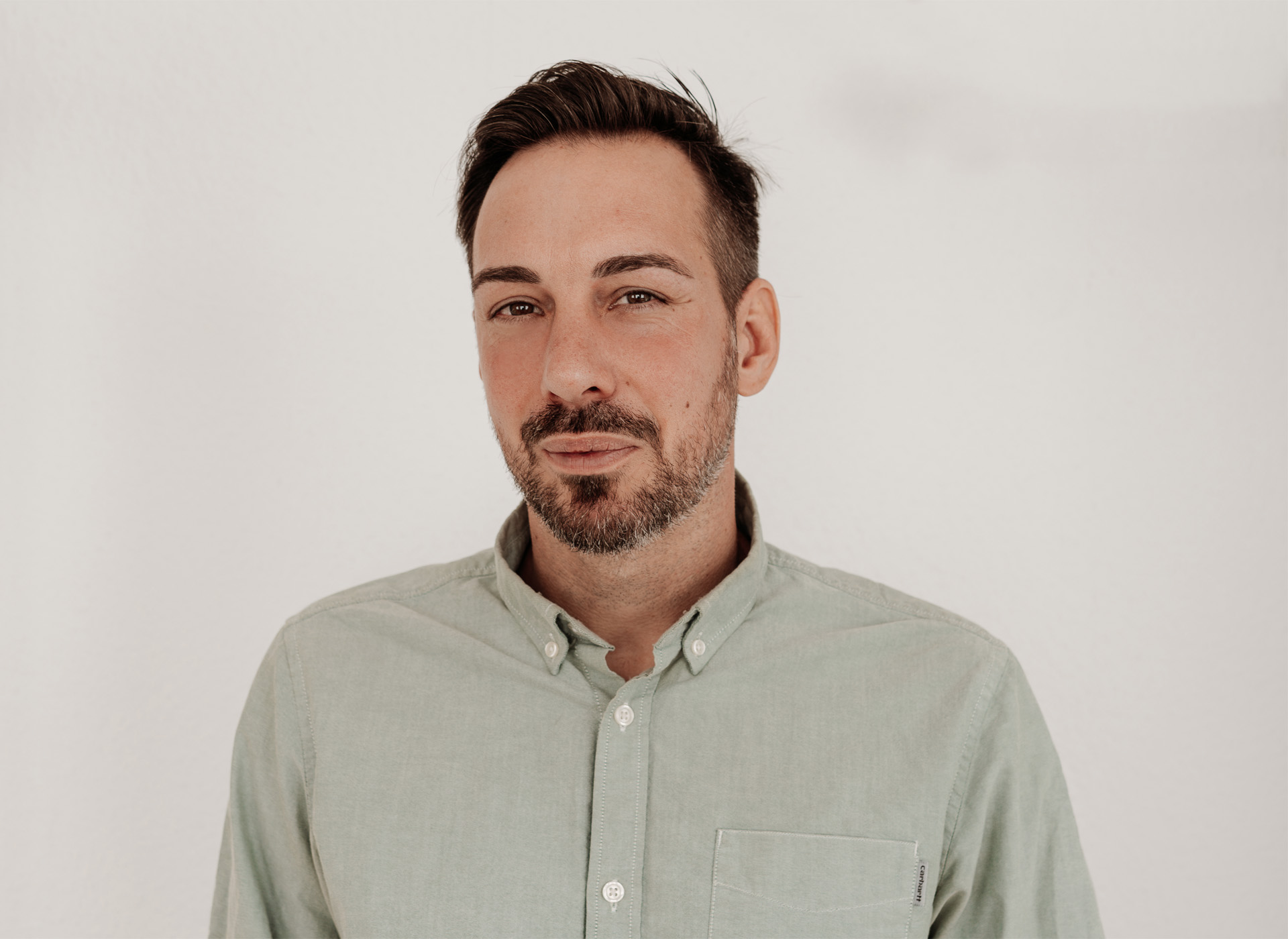 Werte, Vision & Haltung Coach Ben freundlich lächelnd im Portrait – helle Kleidung, neutraler Hintergrund