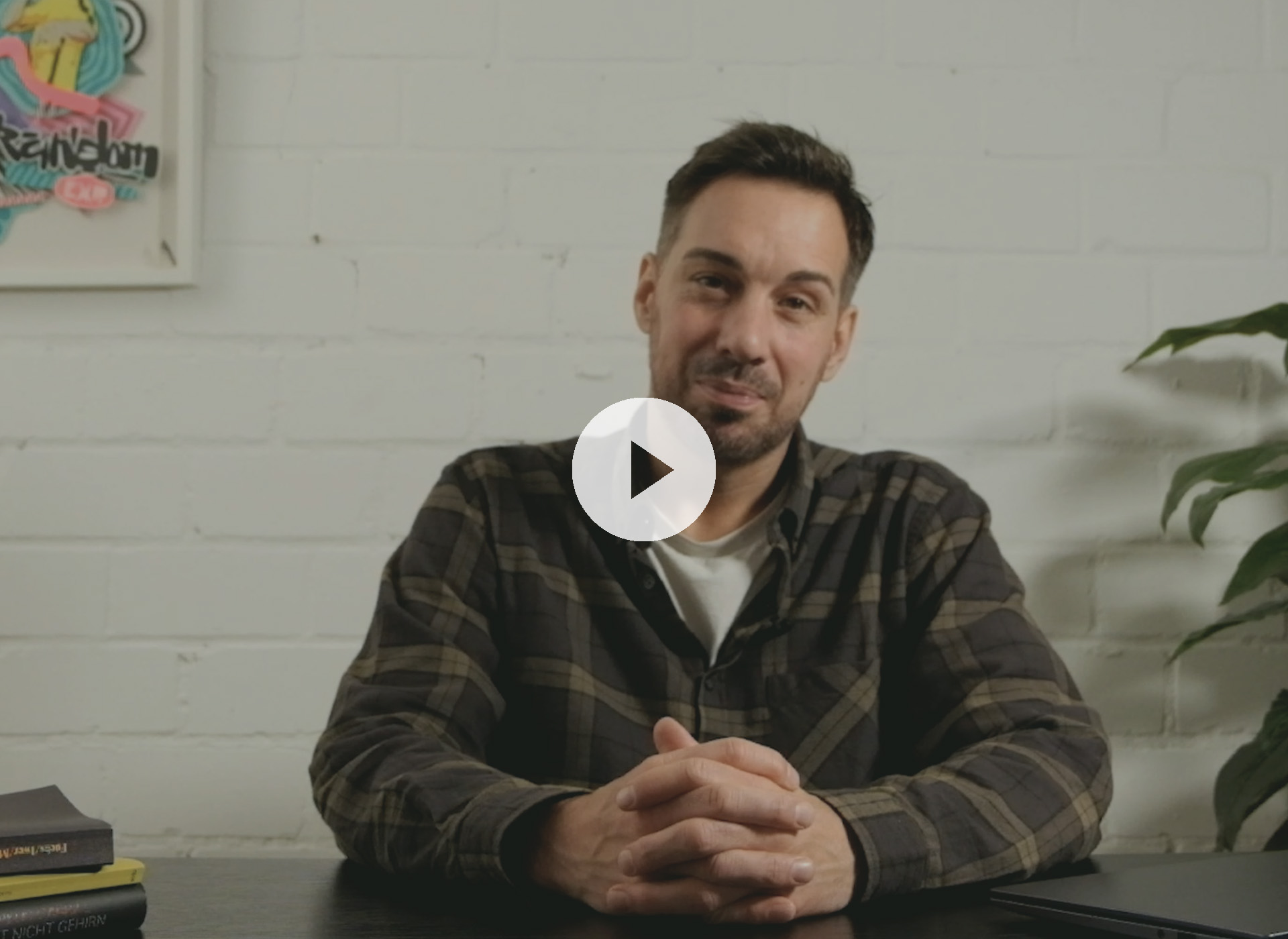 Impulsgebende Seminare und Coaching Coach Ben spricht in einem Video über nachhaltige Seminarwirkung – sitzend vor neutraler Wand mit Pflanze